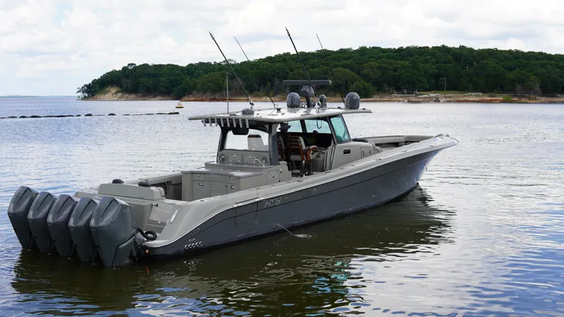 Slide: The Image of 2021 HCB 53 boat with multiple outboard engines on a calm lake. - 6