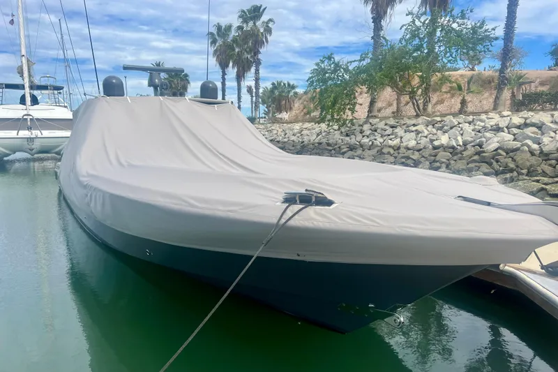 Slide: The Image of Covered 2021 HCB 53 boat docked in a marina with palm trees in the background. - 65