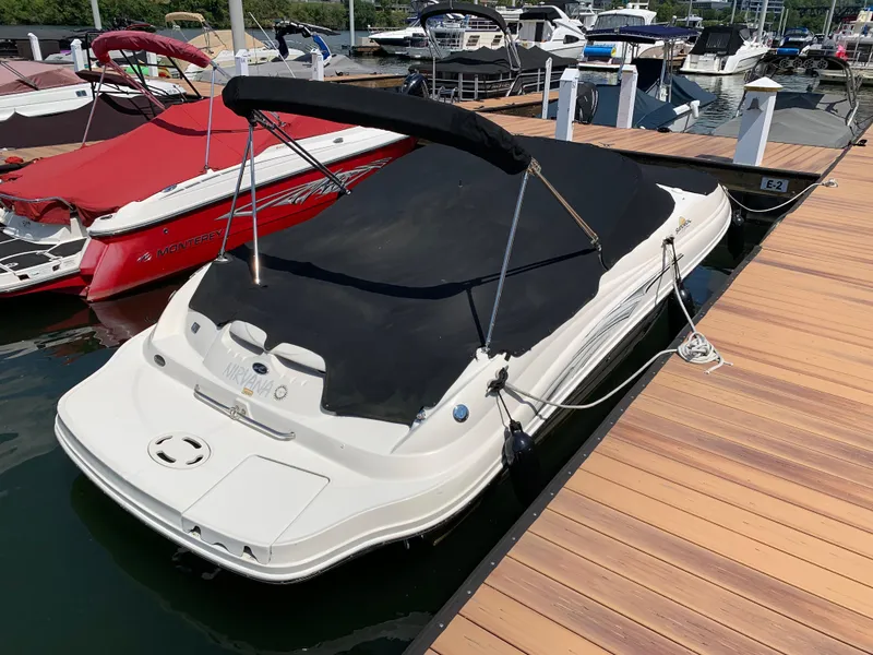 Slide: The Image of 2005 Sea Ray 220 Sundeck boat docked with black cover, marina background. - 11