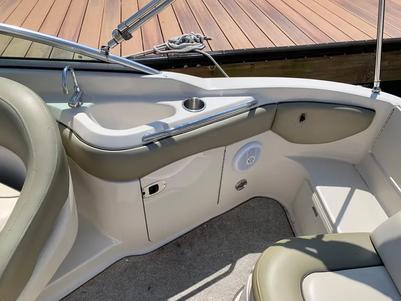 Slide: The Image of 2005 Sea Ray 220 Sundeck interior with seating, cup holder, and speaker near dock. - 9