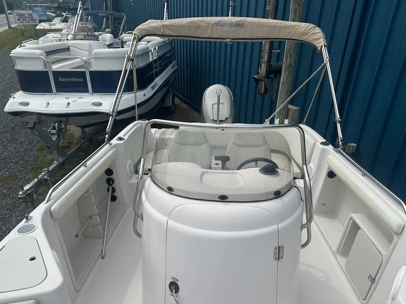 Slide: The Image of 2003 Godfrey Hurricane FD211 boat with seating and steering console, docked near other boats. - 3