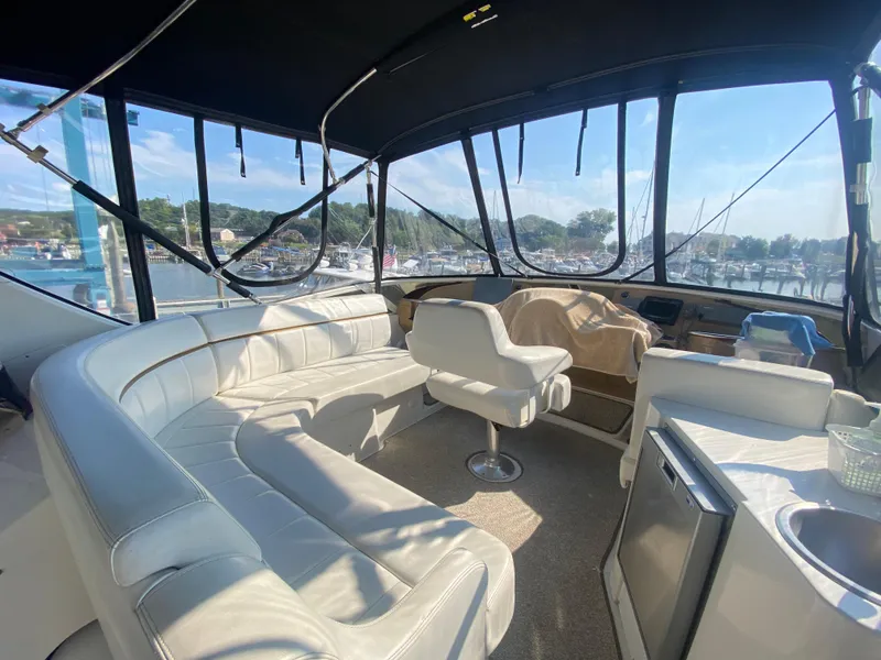 Slide: The Image of Interior of 2002 Carver 444 Cockpit Motor Yacht with white seating and marina view. - 13
