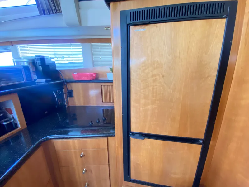 Slide: The Image of 2002 Carver 444 Cockpit Motor Yacht kitchen with wood cabinetry and black countertop. - 18