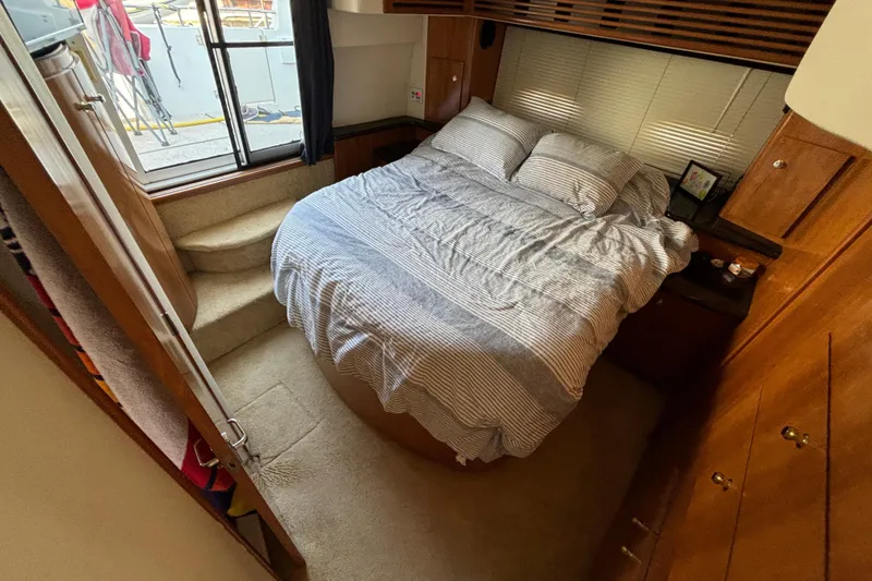Slide: The Image of Cozy bedroom in 2002 Carver 444 Cockpit Motor Yacht with striped bedding and wooden cabinetry. - 2