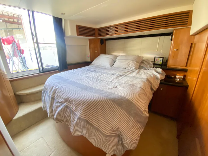 Slide: The Image of Cozy bedroom in 2002 Carver 444 Cockpit Motor Yacht with striped bedding and natural light. - 7