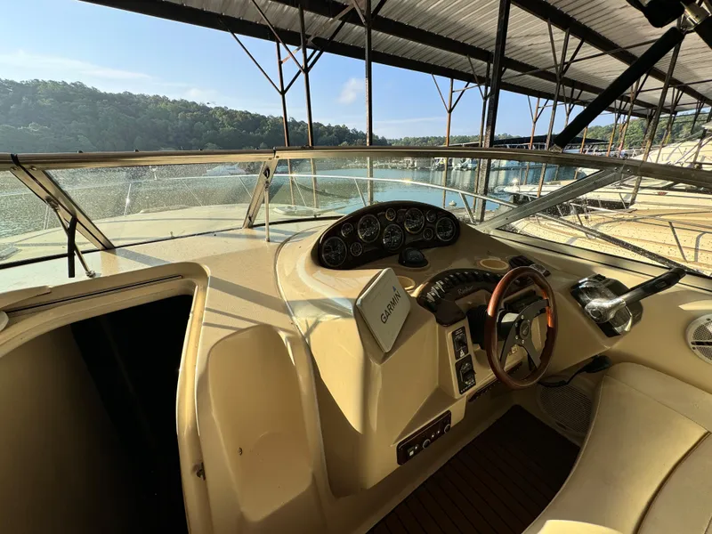Slide: The Image of 2002 Rinker Fiesta Vee 342 boat cockpit with steering wheel and dashboard, docked by a lake. - 37