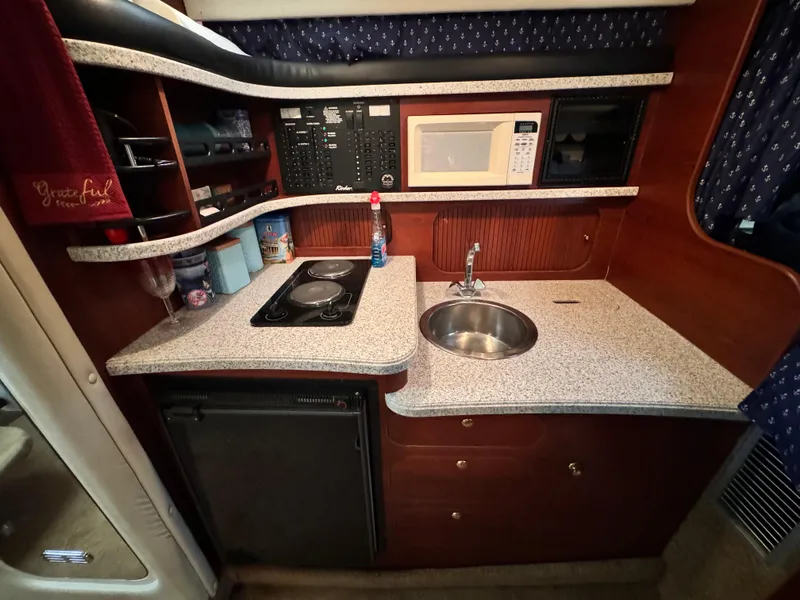 Slide: The Image of 2002 Rinker Fiesta Vee 342 boat kitchen with sink, stove, microwave, and storage cabinets. - 44