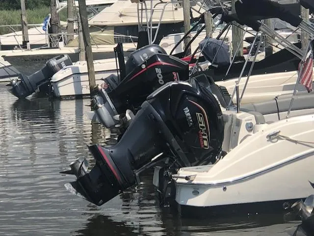 Slide: The Image of NauticStar 243 DC 2022 boat docked with powerful outboard engines in a marina. - 15