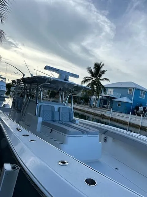 Slide: The Image of 2021 SeaHunter 41 CTS boat docked near a coastal home, under a cloudy sky. - 9