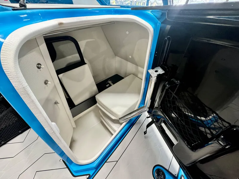 Slide: The Image of 2022 Yamaha Boats 255XD interior storage compartment with white seating and blue trim. - 16