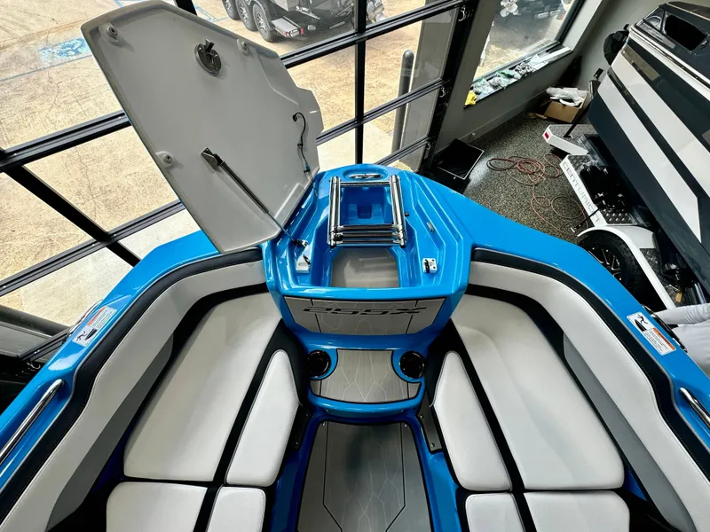 Slide: The Image of 2022 Yamaha Boats 255XD interior with blue and white seating, open storage compartment. - 19