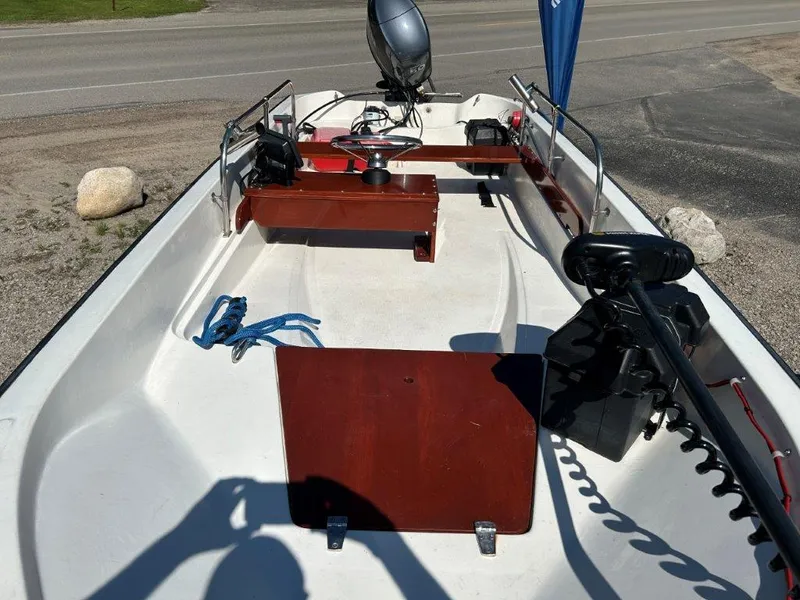 Slide: The Image of 1982 Boston Whaler Sport 15 boat interior with motor and equipment, parked on a sunny day. - 8