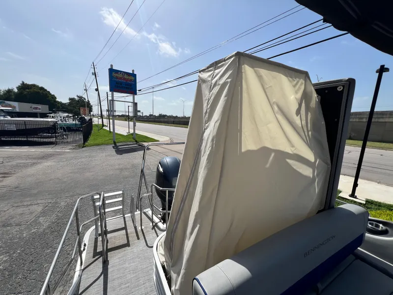 Slide: The Image of 2022 Bennington 23LSB pontoon boat with covered seating area, parked near a road. - 17
