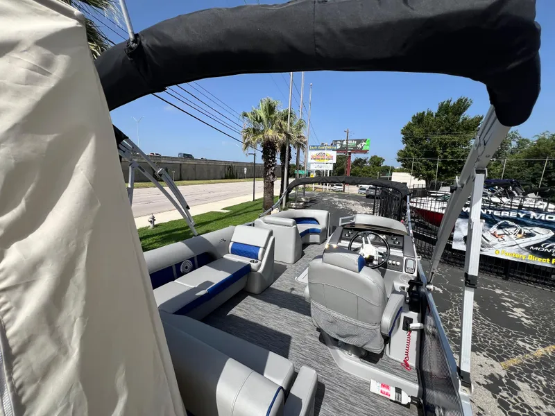 Slide: The Image of 2022 Bennington 23LSB pontoon boat with spacious seating and canopy, parked outdoors. - 18