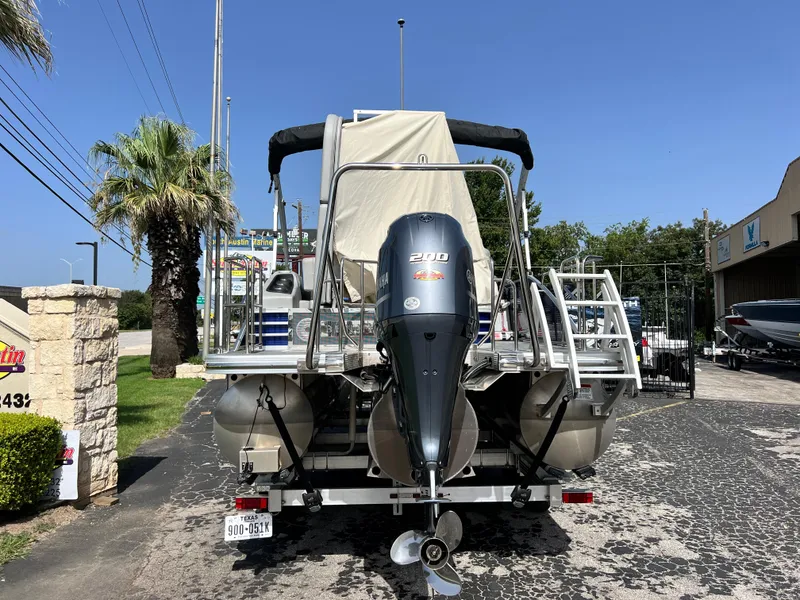 Slide: The Image of 2022 Bennington 23LSB pontoon boat with Yamaha 210 engine, parked outdoors. - 2