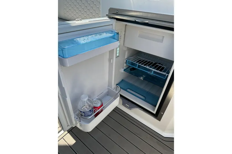 Slide: The Image of Open mini fridge on 2023 Sea Ray SDX 290 Outboard, stocked with drinks. - 26