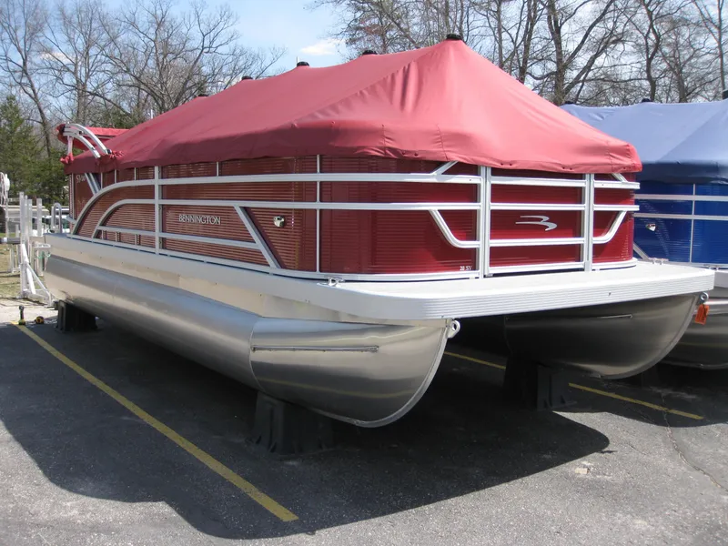 Slide: The Image of 2024 Bennington 20SVSRSR pontoon boat with red cover, parked on a lot. - 1