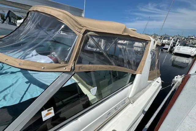 The Image of 1990 Sea Ray 350 Sundancer docked with tan canopy and clear windows. - 0