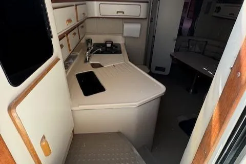 Slide: The Image of Interior of 1990 Sea Ray 350 Sundancer yacht, featuring compact kitchen and seating area. - 16