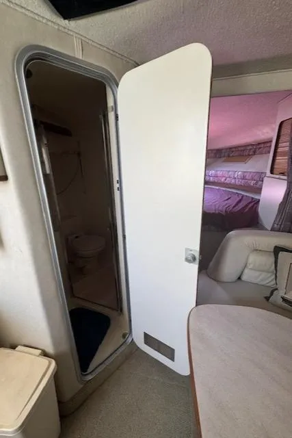 Slide: The Image of 1990 Sea Ray 350 Sundancer interior with open bathroom door and seating area. - 25