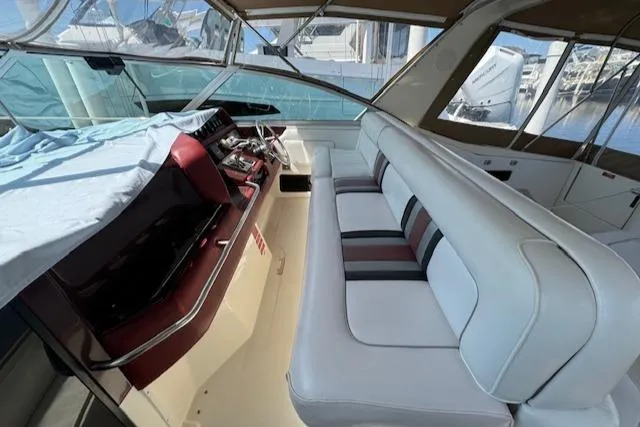 Slide: The Image of 1990 Sea Ray 350 Sundancer interior with white seating and helm, docked at marina. - 5