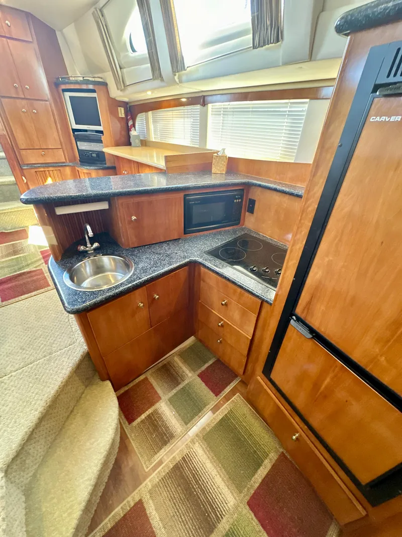 Slide: The Image of 2000 Carver 396 Motor Yacht kitchen with wood cabinetry, sink, microwave, and stove. - 17