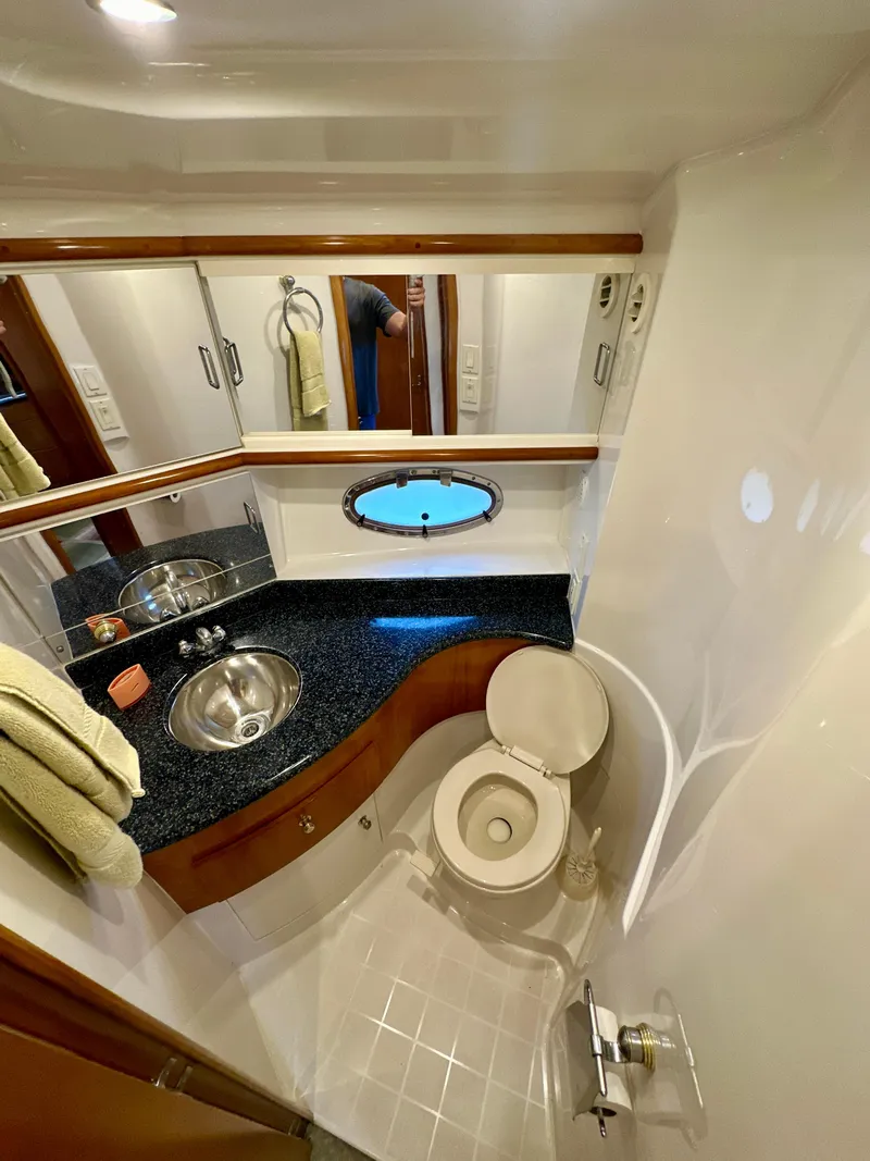Slide: The Image of 2000 Carver 396 Motor Yacht bathroom with sink, toilet, and porthole window. - 24