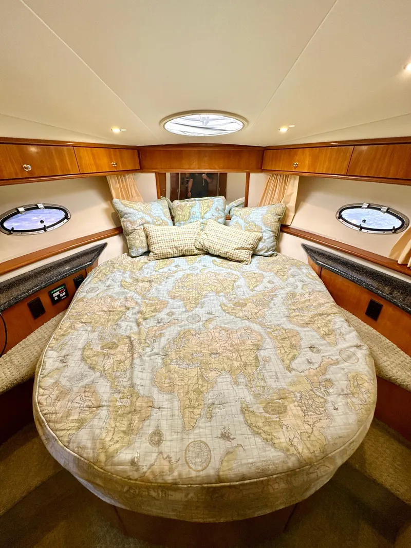 Slide: The Image of Luxurious bedroom in 2000 Carver 396 Motor Yacht with map-themed bedding and elegant wood accents. - 25