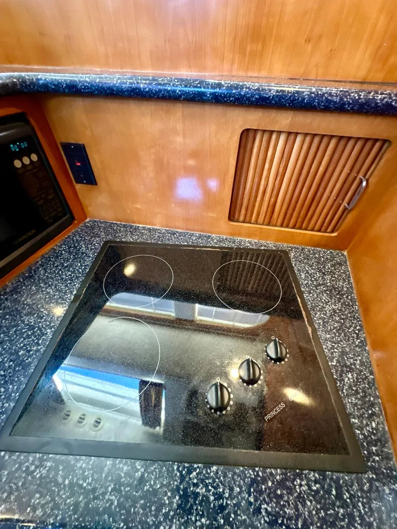 Slide: The Image of 2000 Carver 396 Motor Yacht kitchen with modern stovetop and wood cabinetry. - 19