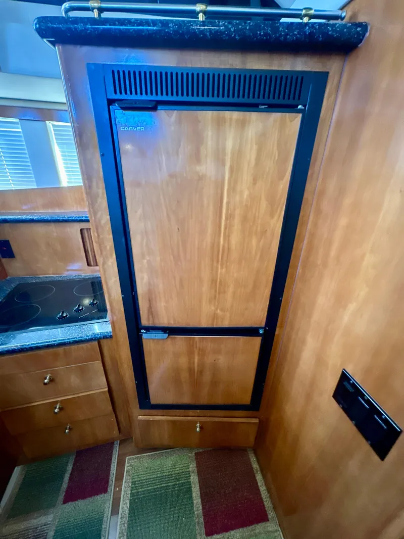 Slide: The Image of 2000 Carver 396 Motor Yacht interior with wooden cabinetry and compact kitchen area. - 20