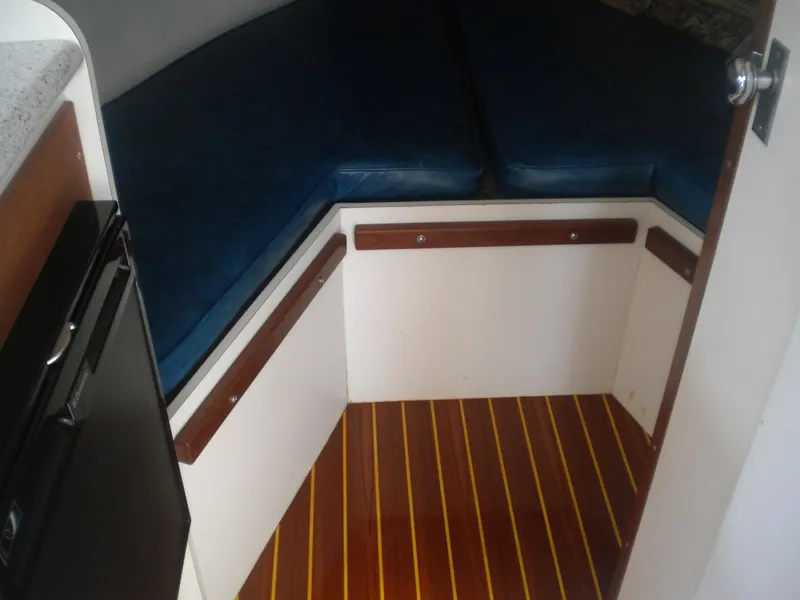Slide: The Image of 1968 Bertram 31 Bahia Mar cabin interior with blue cushions and wooden flooring. - 13