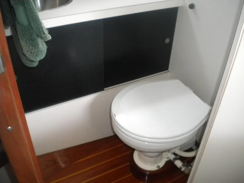 Slide: The Image of 1968 Bertram 31 Bahia Mar boat bathroom with wooden floor and white toilet. - 15
