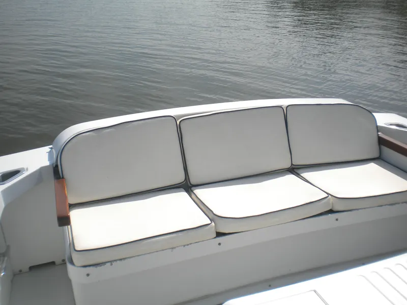 Slide: The Image of White cushioned seating on a 1968 Bertram 31 Bahia Mar boat by the water. - 9