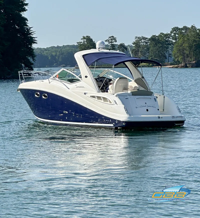 The Image of 2006 Sea Ray 290 Sundancer boat on a serene lake with trees in the background. - 1