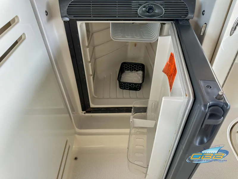 Slide: The Image of Open refrigerator inside 2006 Sea Ray 290 Sundancer boat, showing interior storage space. - 21
