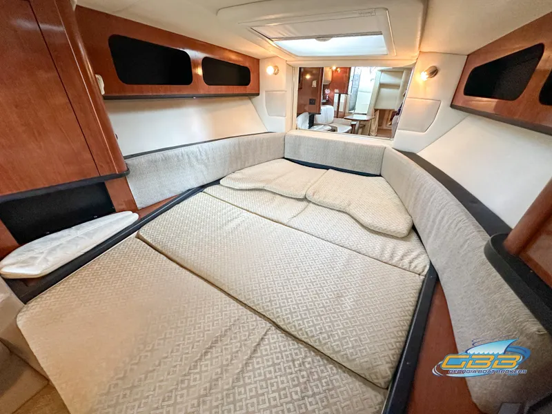 Slide: The Image of Interior cabin of 2006 Sea Ray 290 Sundancer with comfortable bedding and wooden accents. - 25