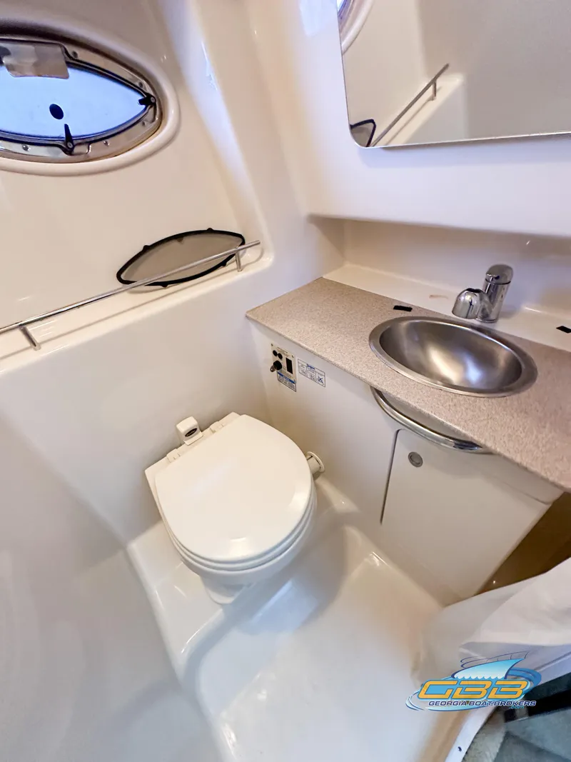 Slide: The Image of 2006 Sea Ray 290 Sundancer bathroom with sink, toilet, and porthole window. - 28