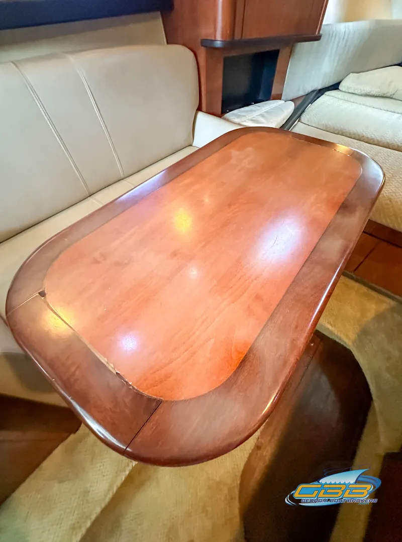 Slide: The Image of 2006 Sea Ray 290 Sundancer interior with wooden table and beige seating. - 33