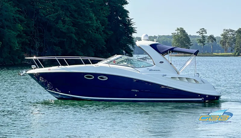 Slide: The Image of 2006 Sea Ray 290 Sundancer boat on a serene lake with lush green trees. - 7