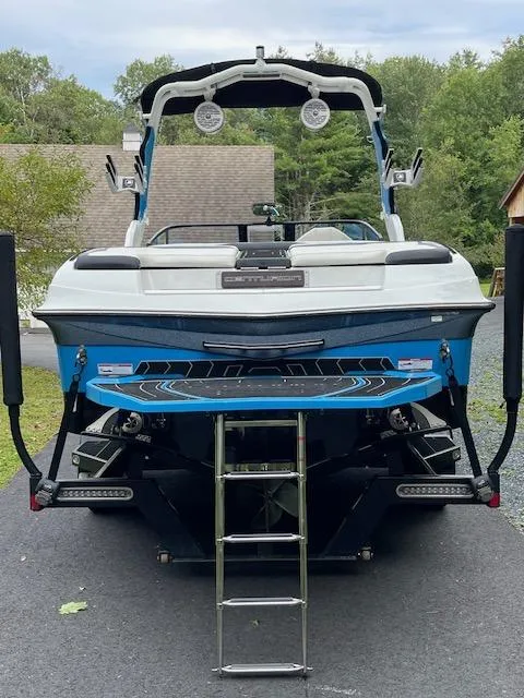 Slide: The Image of 2020 Centurion Ri237 boat, rear view, blue and white, parked on driveway. - 11