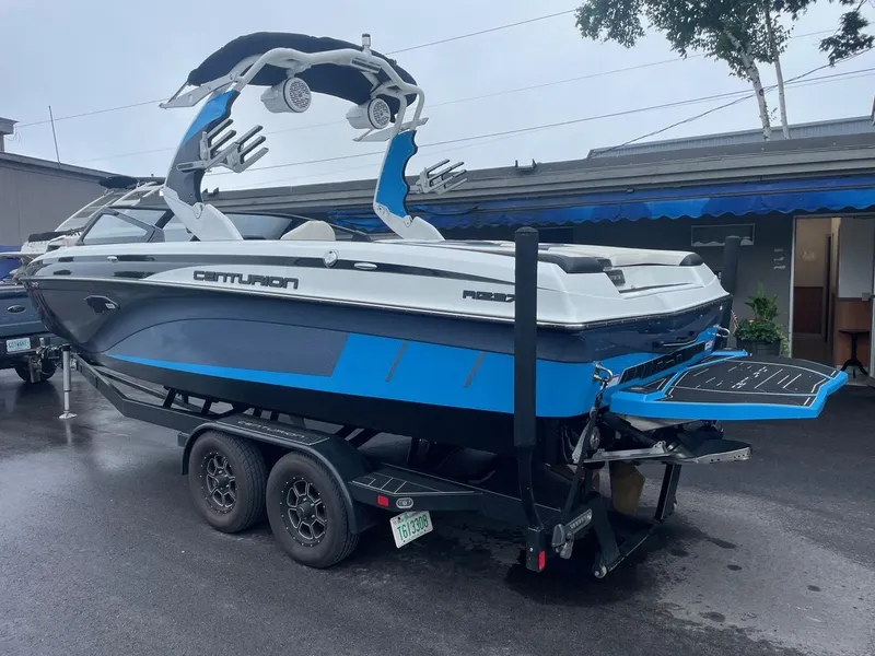 Slide: The Image of 2020 Centurion Ri237 boat on trailer, blue and white design, parked outdoors. - 3