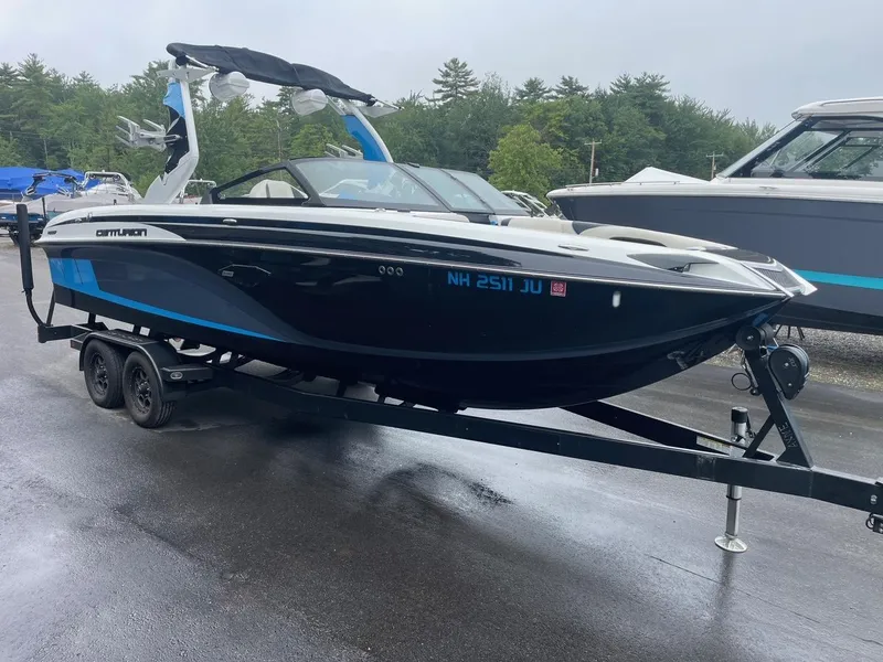 Slide: The Image of 2020 Centurion Ri237 boat on trailer, black and blue design, parked outdoors. - 4