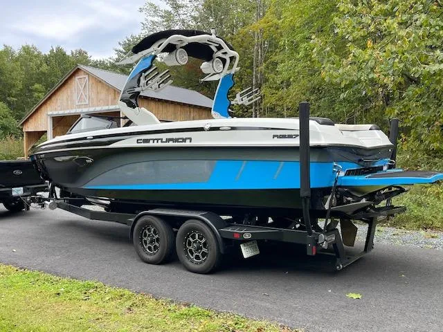 Slide: The Image of 2020 Centurion Ri237 boat on trailer, parked near a wooden barn, surrounded by trees. - 5