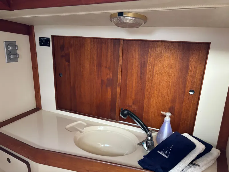 Slide: The Image of 1989 Ericson Yachts 34 bathroom sink with wooden cabinets and toiletries. - 26