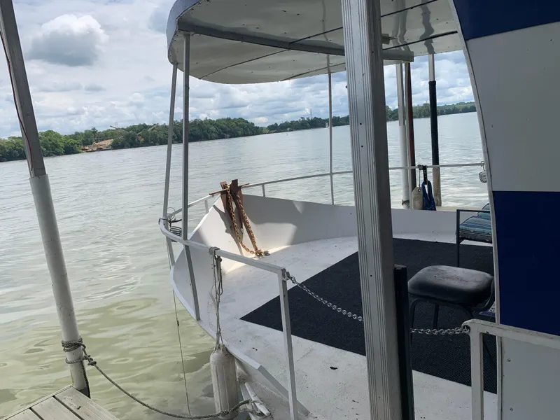 The Image of 1965 Lazy Days Custom houseboat docked on a serene lake under cloudy skies. - 0