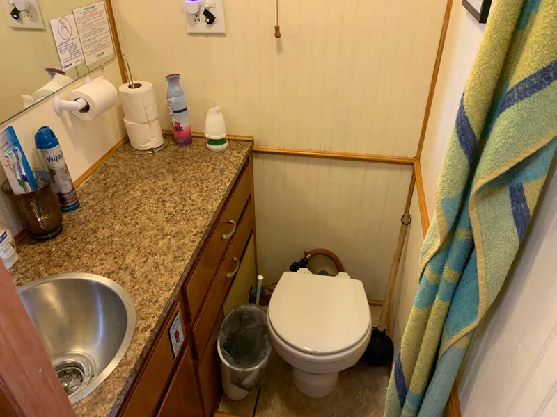 Slide: The Image of Compact 1965 Lazy Days Custom RV bathroom with sink, toilet, and storage cabinets. - 13