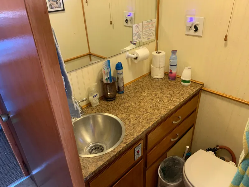 Slide: The Image of Compact 1965 Lazy Days Custom RV bathroom with sink, countertop, and storage cabinets. - 14