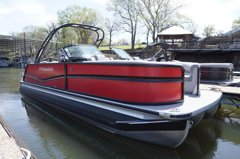 Slide: The Image of 2024 Premier 250 Solaris pontoon boat docked on a calm lake. - 0