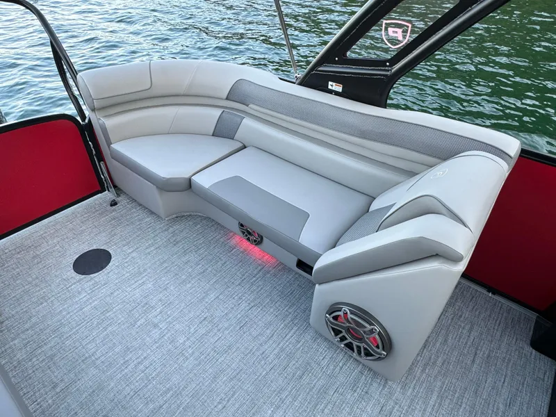 Slide: The Image of 2024 Premier 250 Solaris boat interior with gray seating, red accents, and water view. - 25