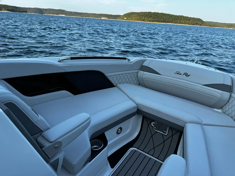 Slide: The Image of 2025 Sea Ray SLX 260 boat interior with luxurious seating on a scenic lake. - 7